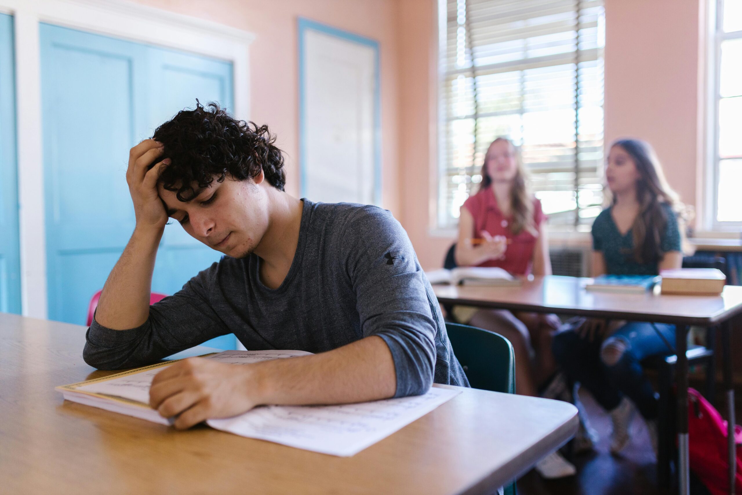 A student appears stressed while studying in a classroom setting, highlighting educational challenges.